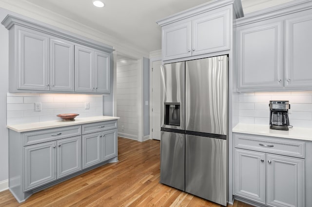 kitchen featuring crown molding, stainless steel fridge with ice dispenser, backsplash, and light hardwood / wood-style floors