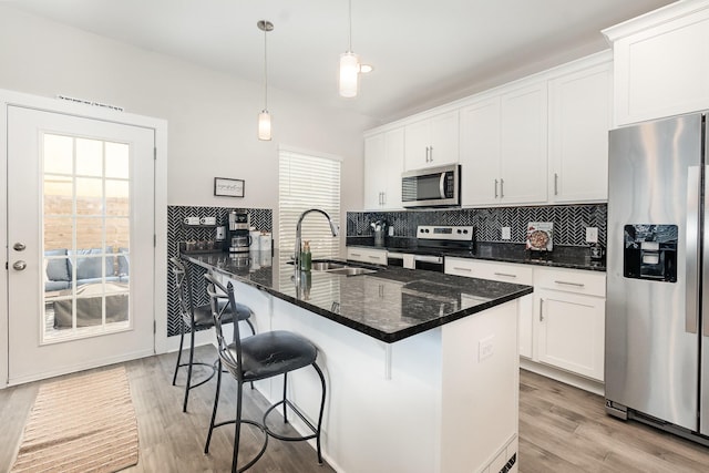 kitchen with decorative light fixtures, white cabinets, dark stone counters, and stainless steel appliances