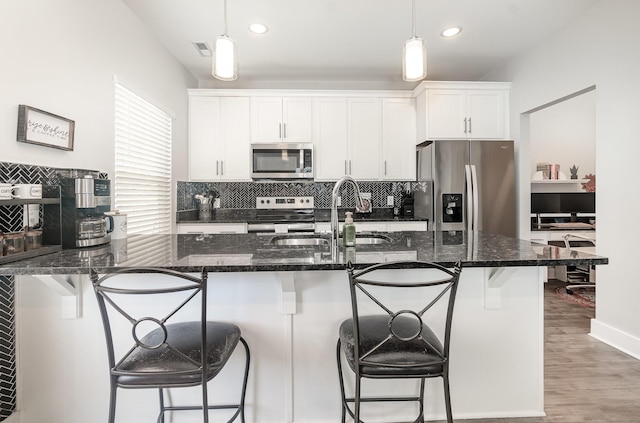 kitchen featuring sink, white cabinetry, appliances with stainless steel finishes, and a kitchen breakfast bar