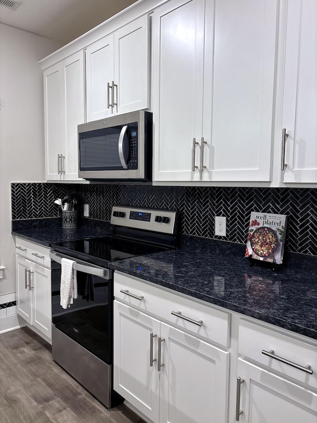 kitchen with white cabinets, tasteful backsplash, dark stone countertops, and appliances with stainless steel finishes