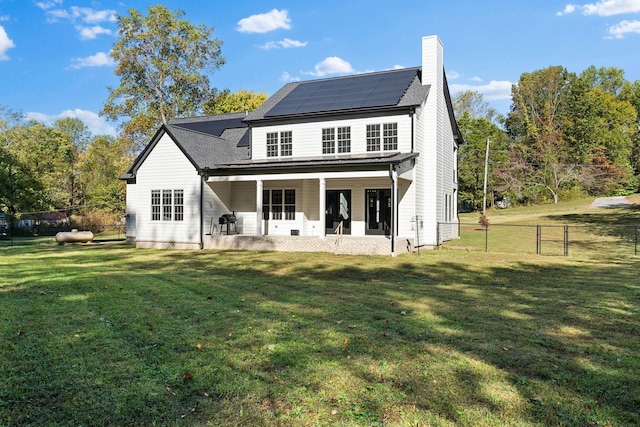 back of property with a patio, a yard, and solar panels