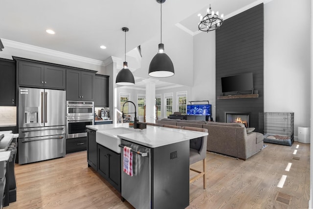 kitchen featuring a kitchen bar, appliances with stainless steel finishes, hanging light fixtures, sink, and a center island with sink