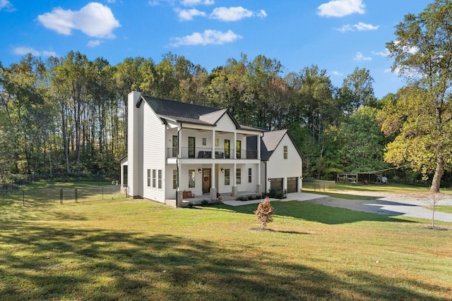 view of front of property with a front yard, a balcony, a porch, and a garage