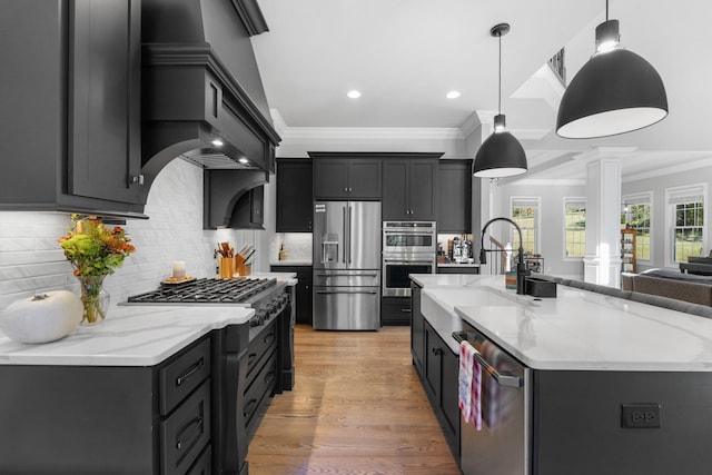 kitchen featuring hanging light fixtures, a center island with sink, stainless steel appliances, and tasteful backsplash