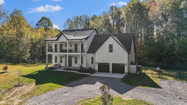 view of front of property featuring a balcony, a front lawn, a garage, and covered porch