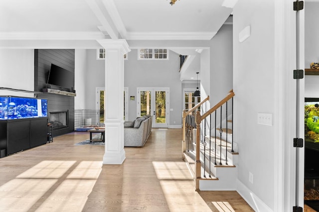 living room featuring a large fireplace, ornamental molding, ornate columns, and french doors