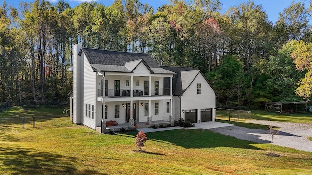 view of front of house featuring a balcony, a porch, a garage, and a front lawn