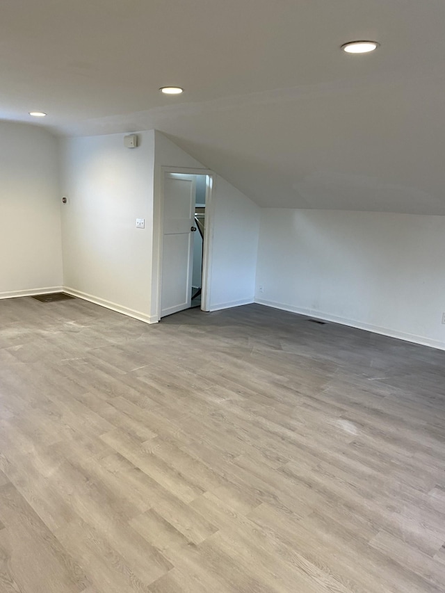 spare room featuring vaulted ceiling and light hardwood / wood-style floors