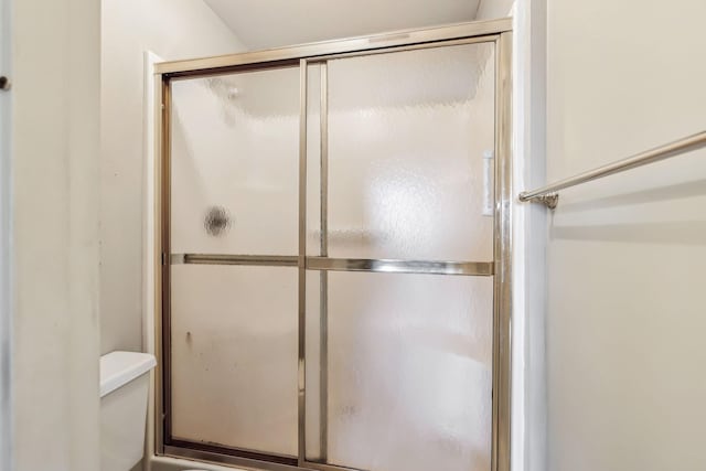 bathroom featuring toilet and a shower with shower door