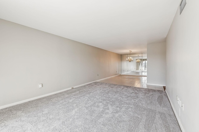 empty room featuring light colored carpet and a chandelier