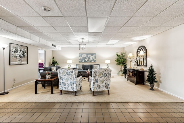 living room with carpet flooring and a paneled ceiling