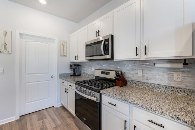 kitchen featuring backsplash, white cabinets, light stone countertops, light hardwood / wood-style floors, and stainless steel appliances