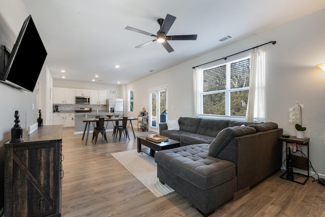 living room with light hardwood / wood-style flooring and ceiling fan