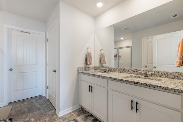 bathroom featuring a shower with shower door and vanity