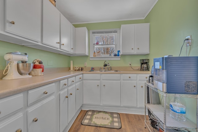 kitchen with sink, light wood-type flooring, white cabinetry, and crown molding