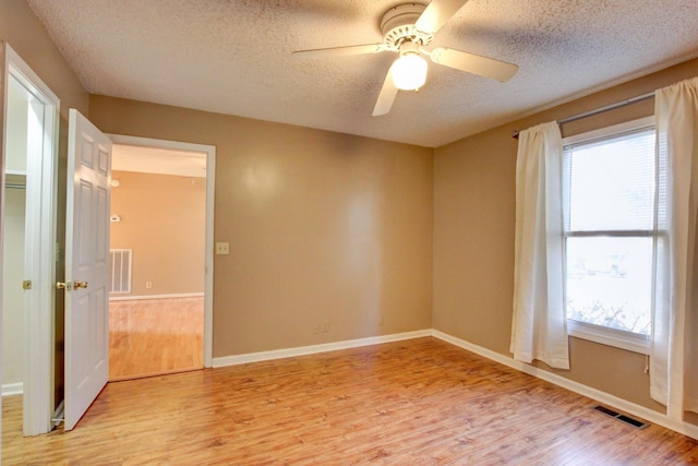 empty room featuring ceiling fan, light hardwood / wood-style flooring, and a textured ceiling