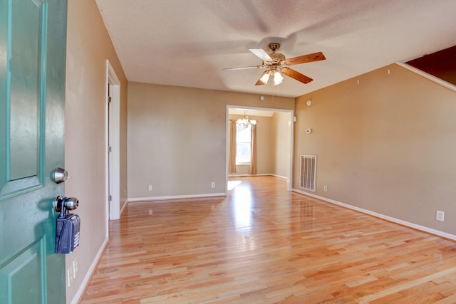 entryway featuring ceiling fan with notable chandelier, a textured ceiling, and light wood-type flooring