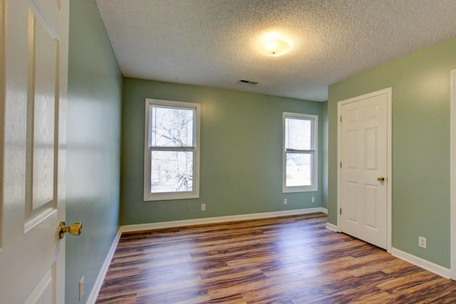 unfurnished room with dark hardwood / wood-style floors and a textured ceiling