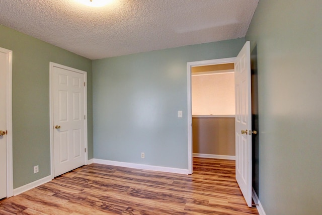 unfurnished bedroom with a closet, a textured ceiling, and light hardwood / wood-style flooring