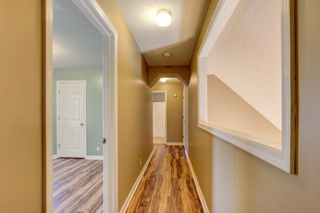 hallway with wood-type flooring and a textured ceiling