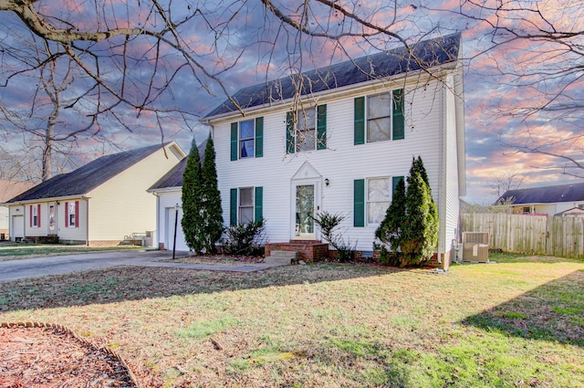 colonial inspired home featuring central air condition unit and a lawn