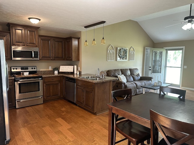 kitchen featuring pendant lighting, hardwood / wood-style floors, appliances with stainless steel finishes, sink, and kitchen peninsula