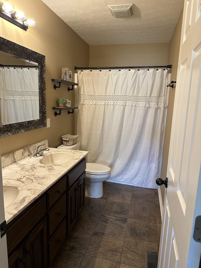 bathroom with vanity, toilet, curtained shower, and a textured ceiling