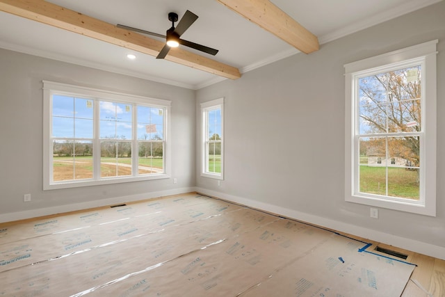 empty room featuring ceiling fan, plenty of natural light, ornamental molding, and beam ceiling