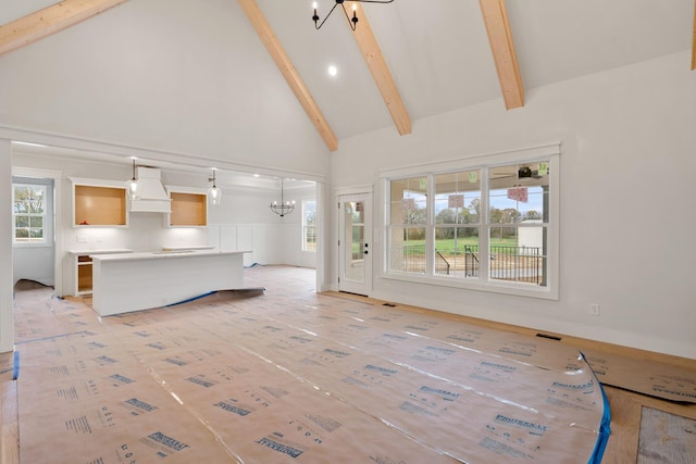 unfurnished living room featuring high vaulted ceiling, beamed ceiling, and a chandelier