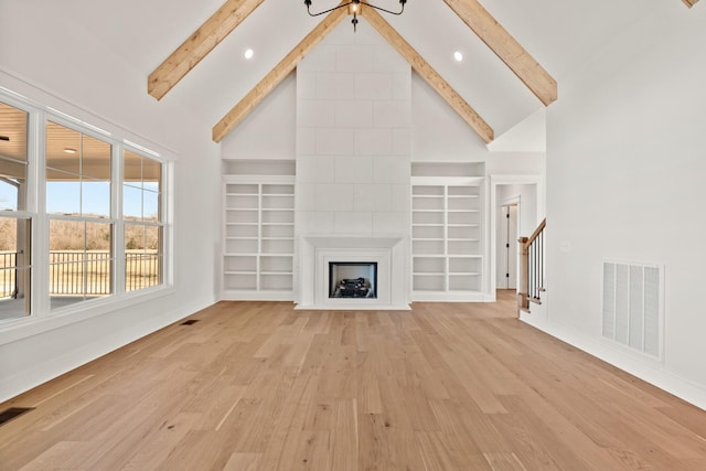 unfurnished living room with light wood-style floors, a fireplace, visible vents, and beamed ceiling