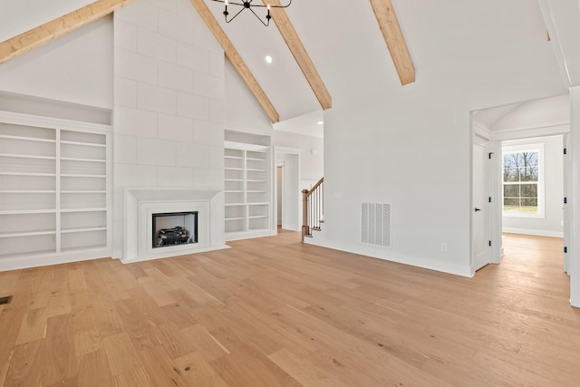 unfurnished living room featuring a large fireplace, visible vents, stairway, and light wood-style flooring