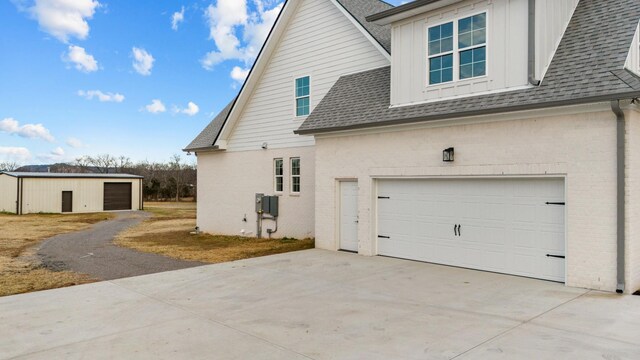 view of property exterior with driveway, brick siding, and roof with shingles