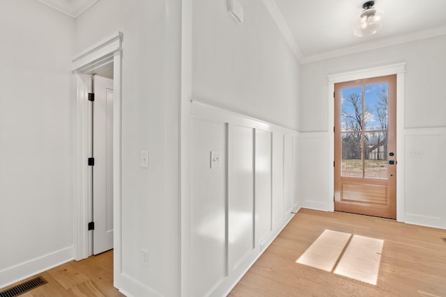 entrance foyer with light wood finished floors, visible vents, a wainscoted wall, and ornamental molding