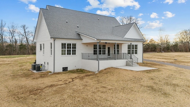 rear view of house with roof with shingles, covered porch, cooling unit, a yard, and a patio area