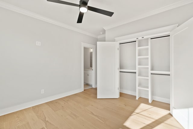 unfurnished bedroom featuring ceiling fan, a barn door, baseboards, light wood-style floors, and ornamental molding