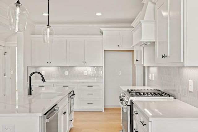 kitchen with premium range hood, white cabinets, appliances with stainless steel finishes, light stone countertops, and pendant lighting