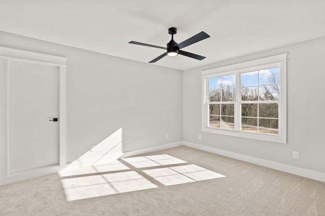 spare room with ceiling fan, baseboards, and light colored carpet