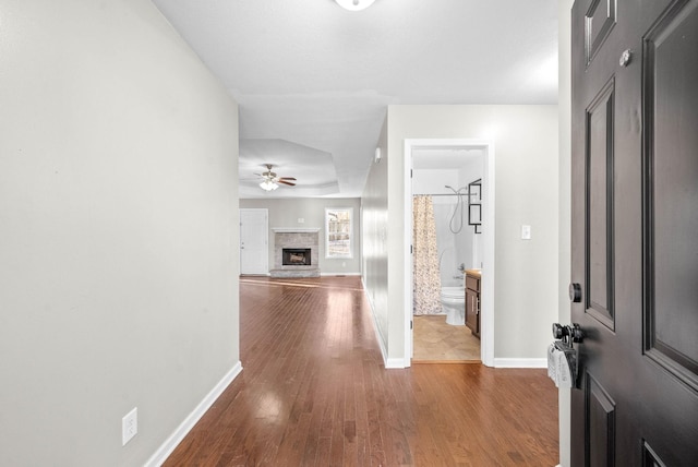 foyer with ceiling fan, hardwood / wood-style floors, and a brick fireplace