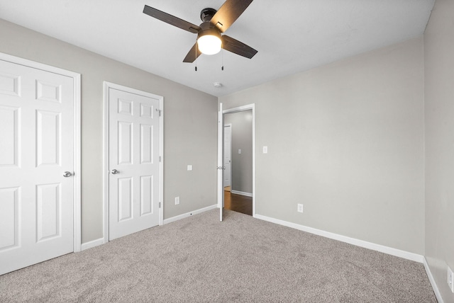 unfurnished bedroom with carpet floors, two closets, and ceiling fan