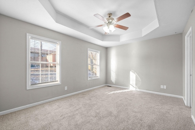 carpeted empty room featuring a raised ceiling and ceiling fan