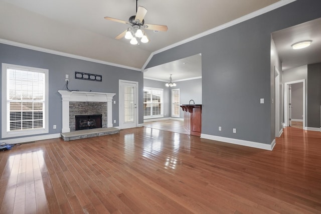 unfurnished living room with a fireplace, a wealth of natural light, ornamental molding, and vaulted ceiling