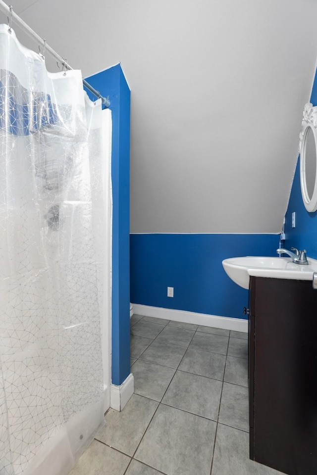 bathroom featuring tile patterned flooring, vanity, and vaulted ceiling