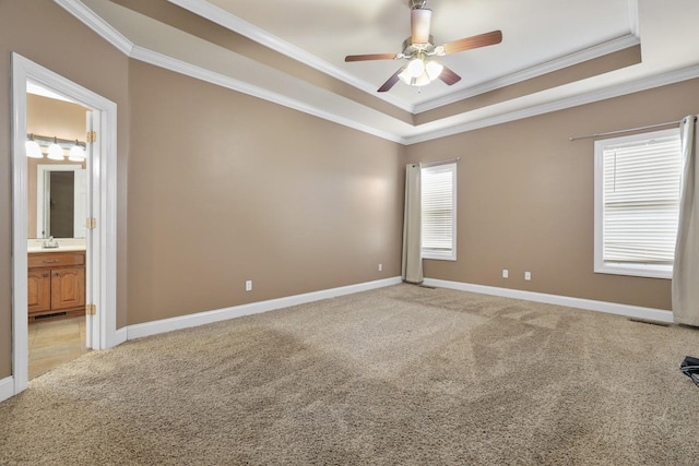 carpeted spare room with ceiling fan, ornamental molding, and a raised ceiling