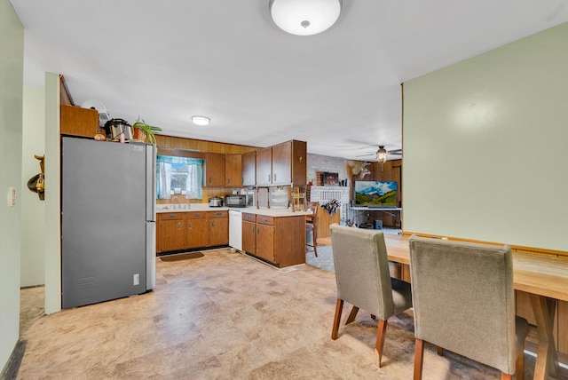 kitchen with white dishwasher, kitchen peninsula, ceiling fan, and stainless steel refrigerator