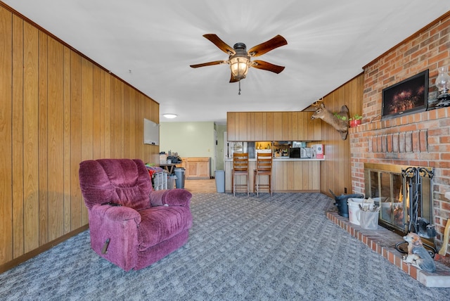 living room featuring a fireplace, carpet flooring, wooden walls, and ceiling fan