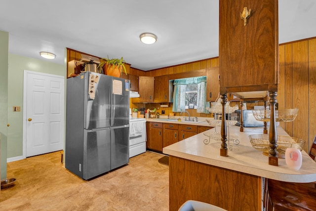 kitchen featuring sink, electric stove, stainless steel fridge, and kitchen peninsula