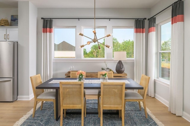 dining space with a chandelier, a healthy amount of sunlight, and light hardwood / wood-style flooring