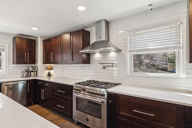 kitchen with decorative backsplash, dark wood-type flooring, wall chimney exhaust hood, and appliances with stainless steel finishes