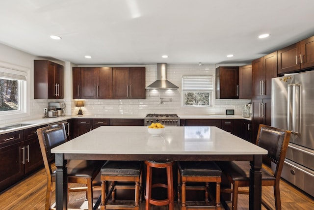 kitchen with wall chimney exhaust hood, a breakfast bar area, a kitchen island, and premium appliances