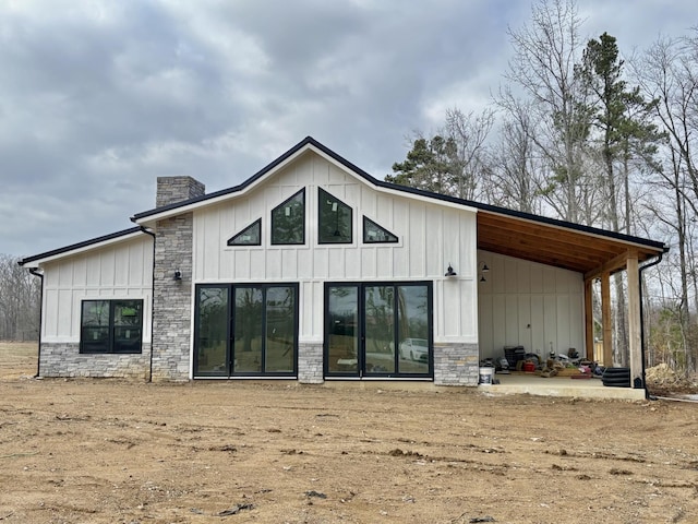 rear view of house featuring a chimney, board and batten siding, and stone siding